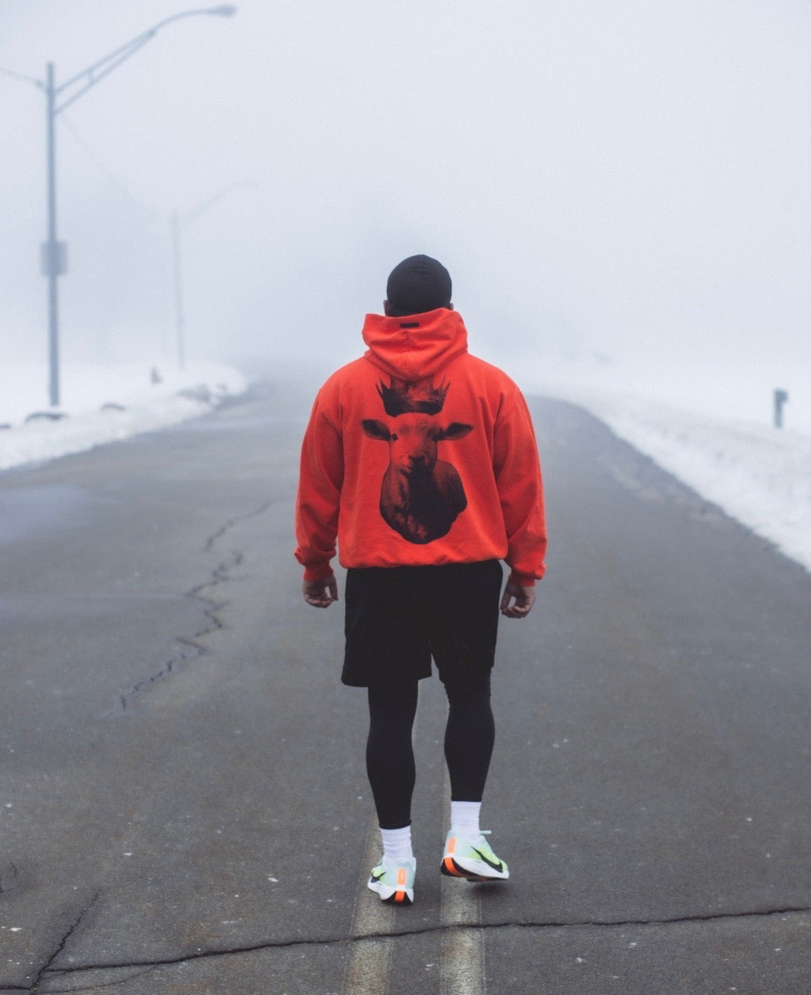 Person wearing a red hoodie with a lamb design on a foggy road